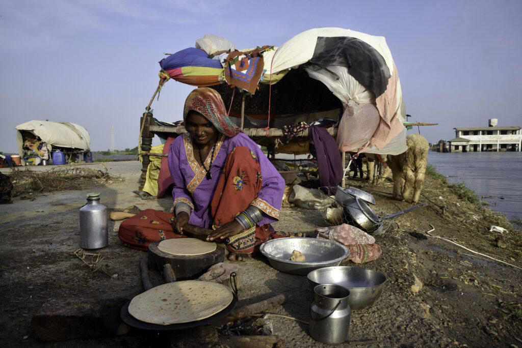 A woman in Pakistan cooks bread outside her tent in 2022, when millions were left homeless after devastating floods.