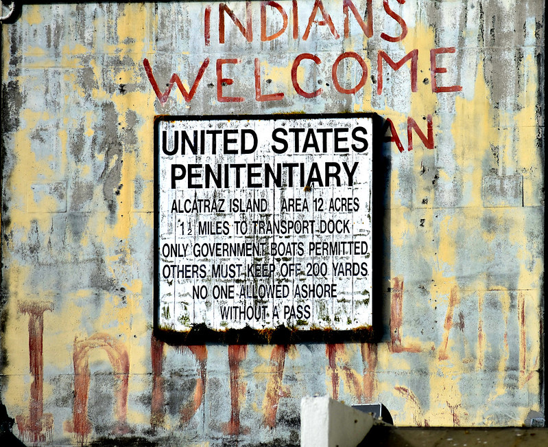 Sign for San Francisco's Alcatraz Island US penitentiary with "Indians Welcome" painted behind it