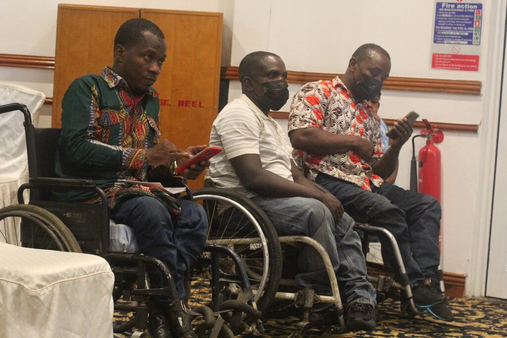 Three men living with disabilities in Ghana, sitting in wheelchairs at the 2022 Global Disability Summit co-hosted by Ghana.