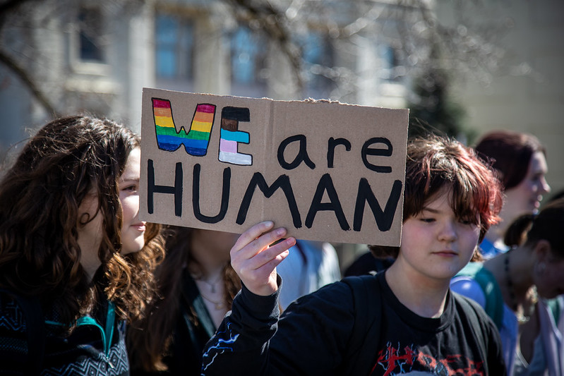 Middle-school-aged students carrying a handmade rainbow painted sign reading "We are human."
