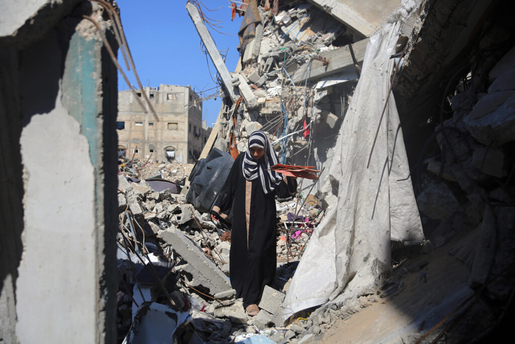 After the ceasefire in Gaza, what comes next? Photo shows a woman walking through the rubble of bombed building in Gaza.