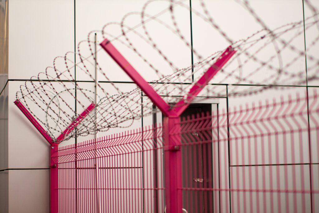 Image shows a barbed wire fence in a prison yard. "Hostage diplomacy," when governments detain foreign citizens for leverage, was the target of a Trump executive order in September 2025.