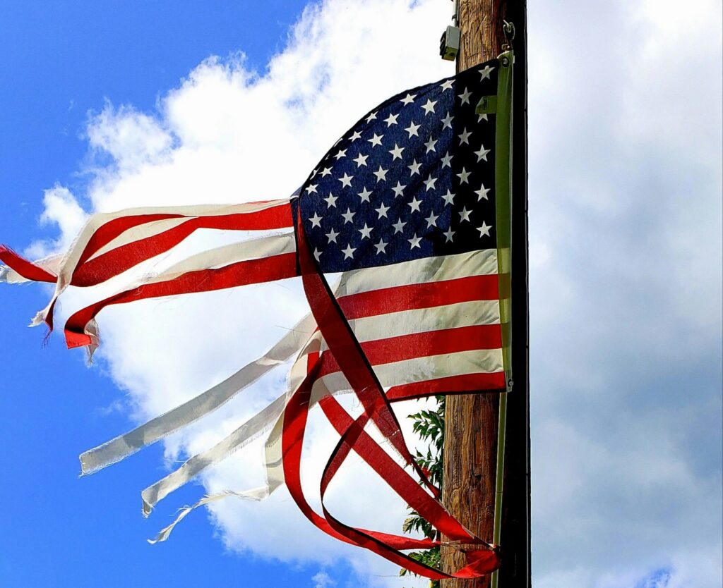 Image shows a tattered U.S. flag.